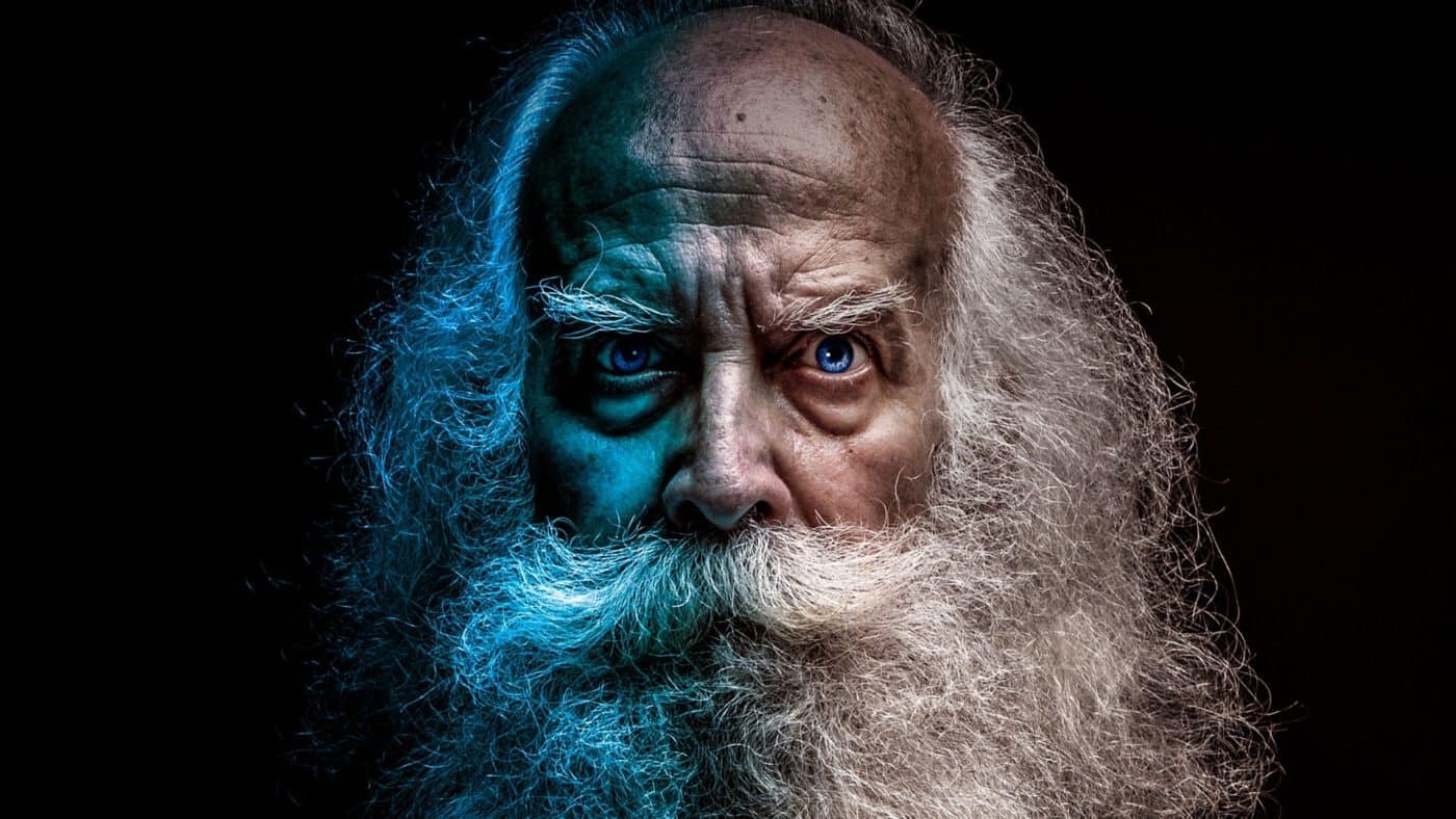 Old man with beard against black background